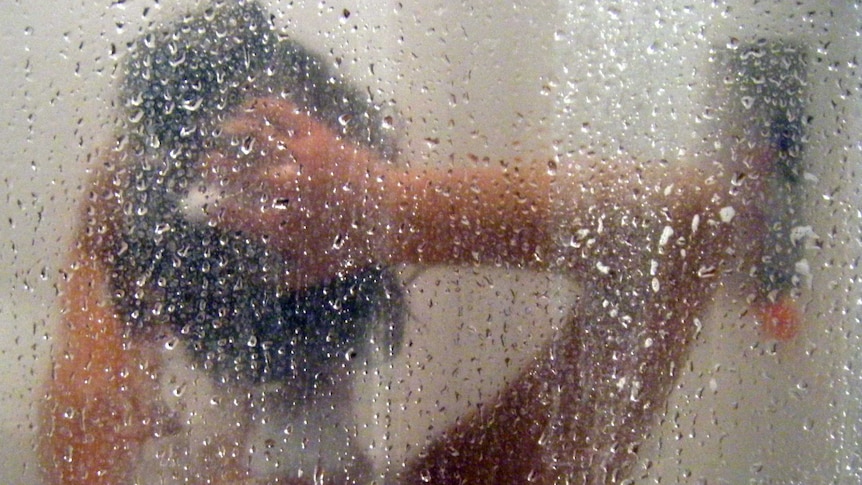 A woman shampoos her hair in a shower