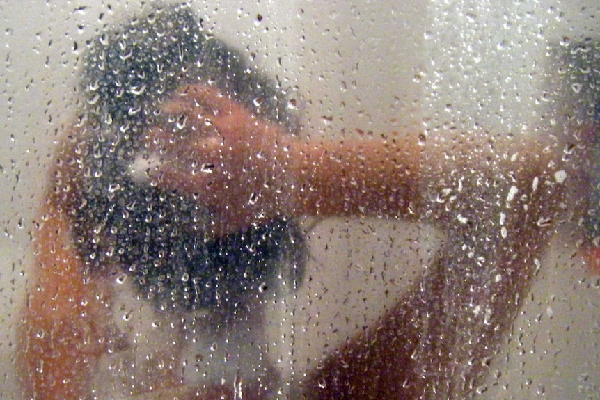 A woman shampoos her hair in a shower