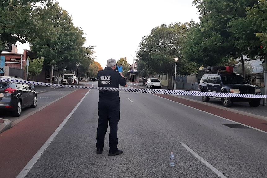 A forensics officer takes photos at a crime scene