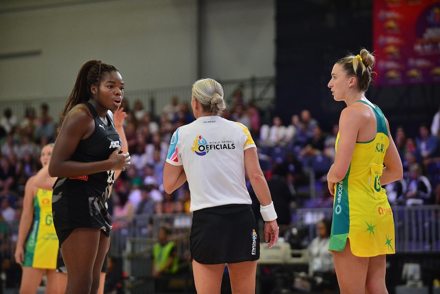 Umpire chats with tall Silver Ferns shooter as Australian defender watches on