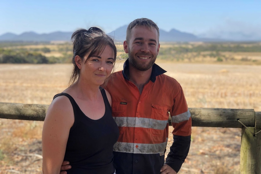 Nicole Holdaway and Eric Verhoeven stand in front of a field.