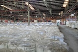 A warehouse with many rows of soft plastics in big white bags.