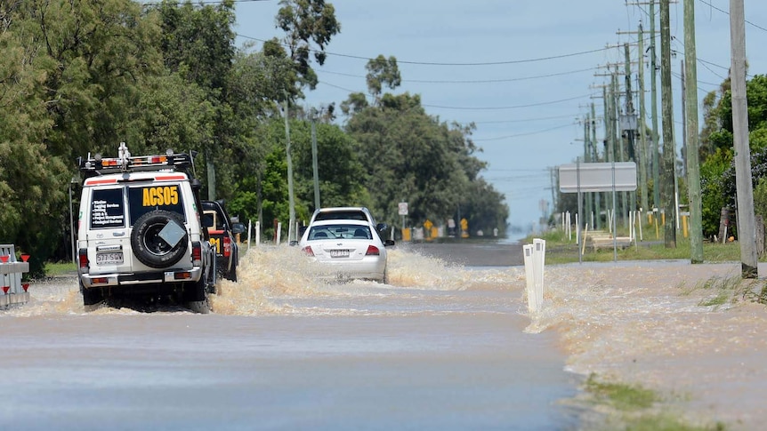 Cars cross a flooded road in Dalby
