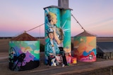 Four silos are painted in bright colours with images reflecting farm life
