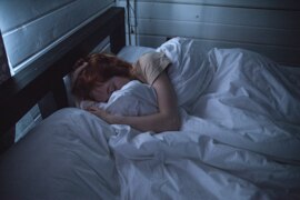 Woman sleeping with her face hidden by bedding