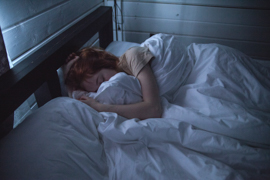 Woman sleeping with her face hidden by bedding