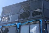 A two story house with lots of glass windows, most smashed by hail.