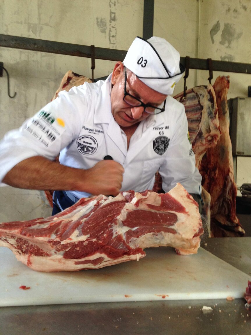 Independent butcher Trevor Hill cuts up a carcass in front of a group of beef farmers.