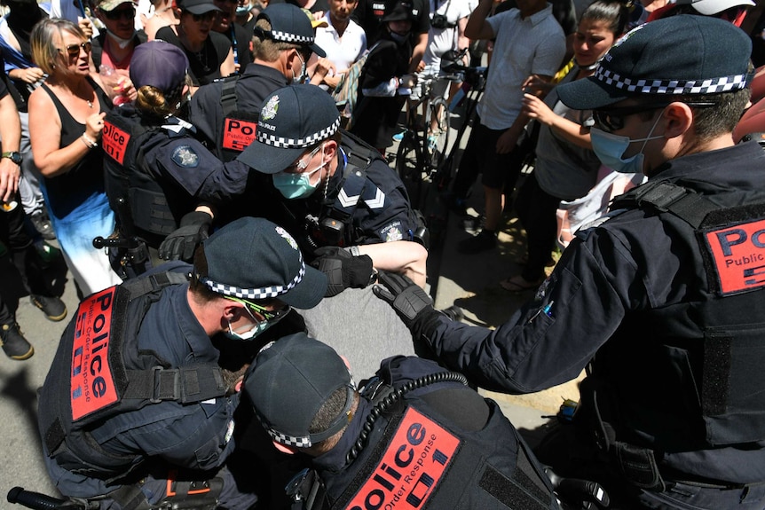 Police try to arrest a man in the middle of a protest.