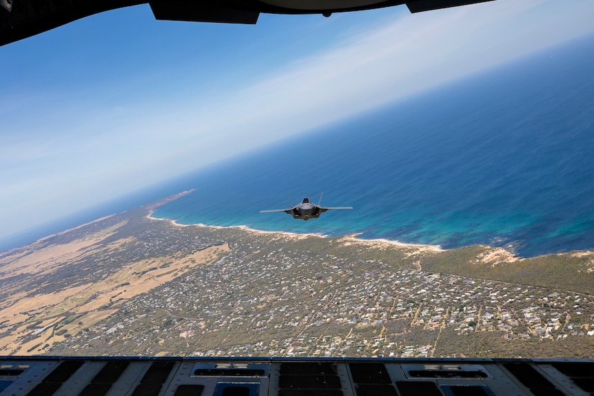 A high shot of a fighter jet flying over Melbourne taken from another plane behind it