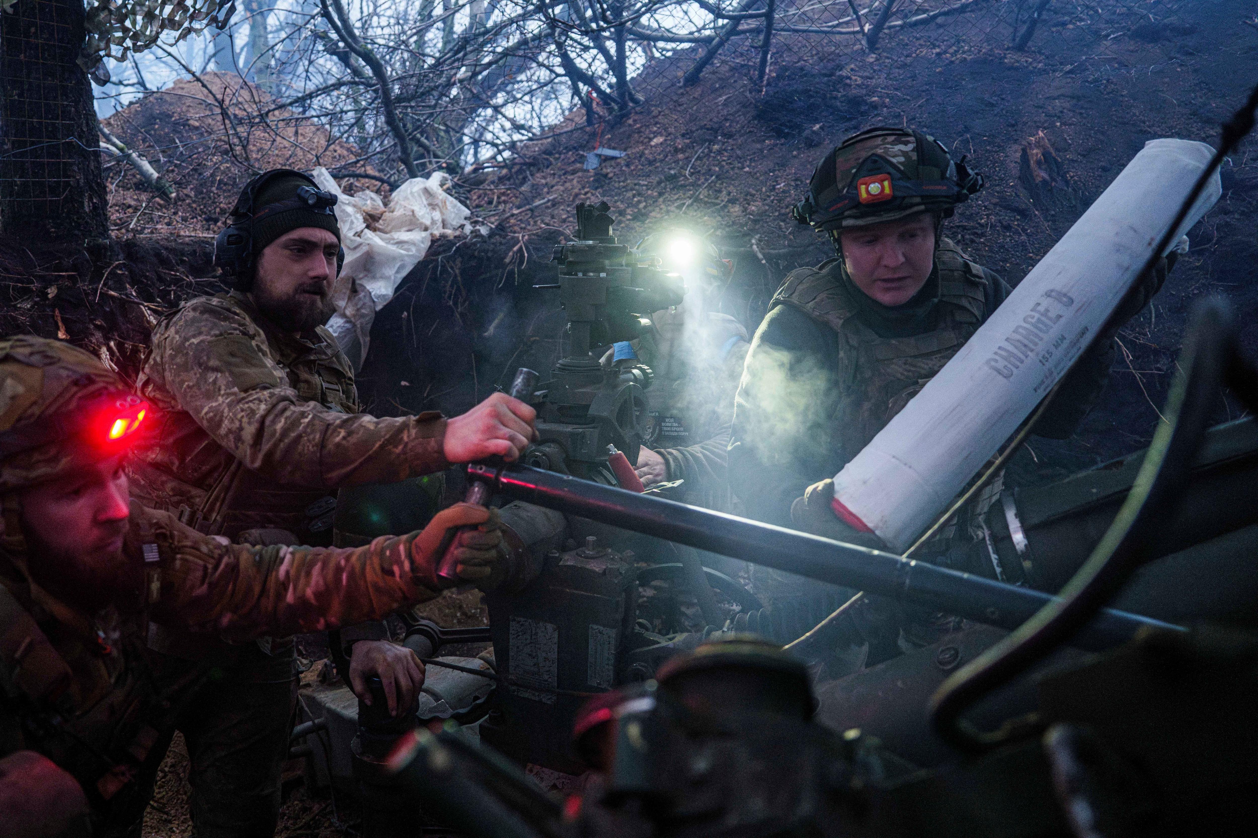 Soldiers load a portable howitzer.
