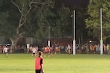 a blurry yellow ball kicked high into the night sky as a crowd watches on