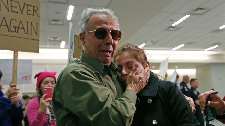 An Iranian green card holder cries on the shoulders of her father after being released at Dallas airport