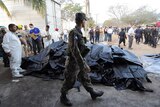 A Honduran soldier stands guard as forensic workers remove corpses