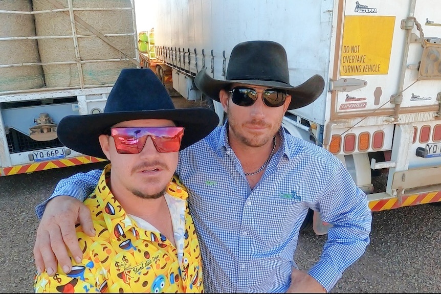 Two men in blue and yellow shirts and cowboy hats stand next to eachother