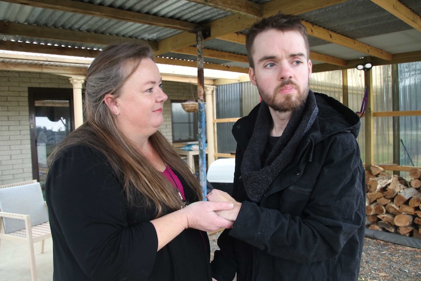 Lyn Cleaver holding her son Jeremy's hands out the front of a house.