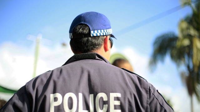 A police officer in uniform, seen from behind.