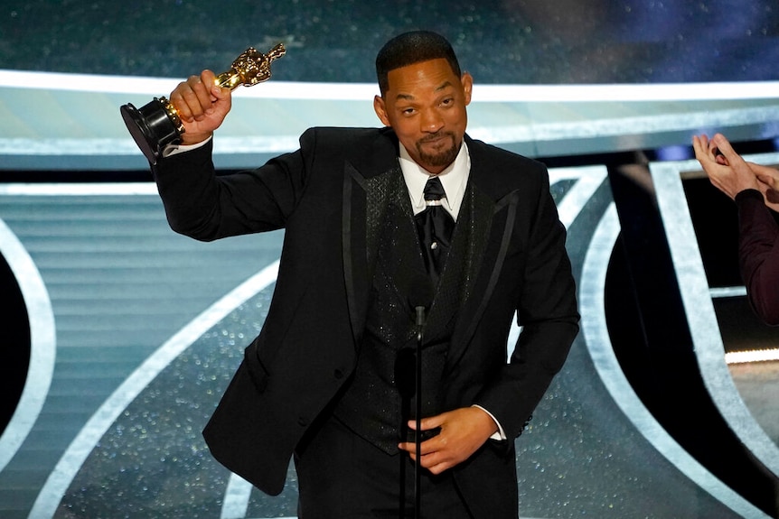Will Smith with his trophy on stage.