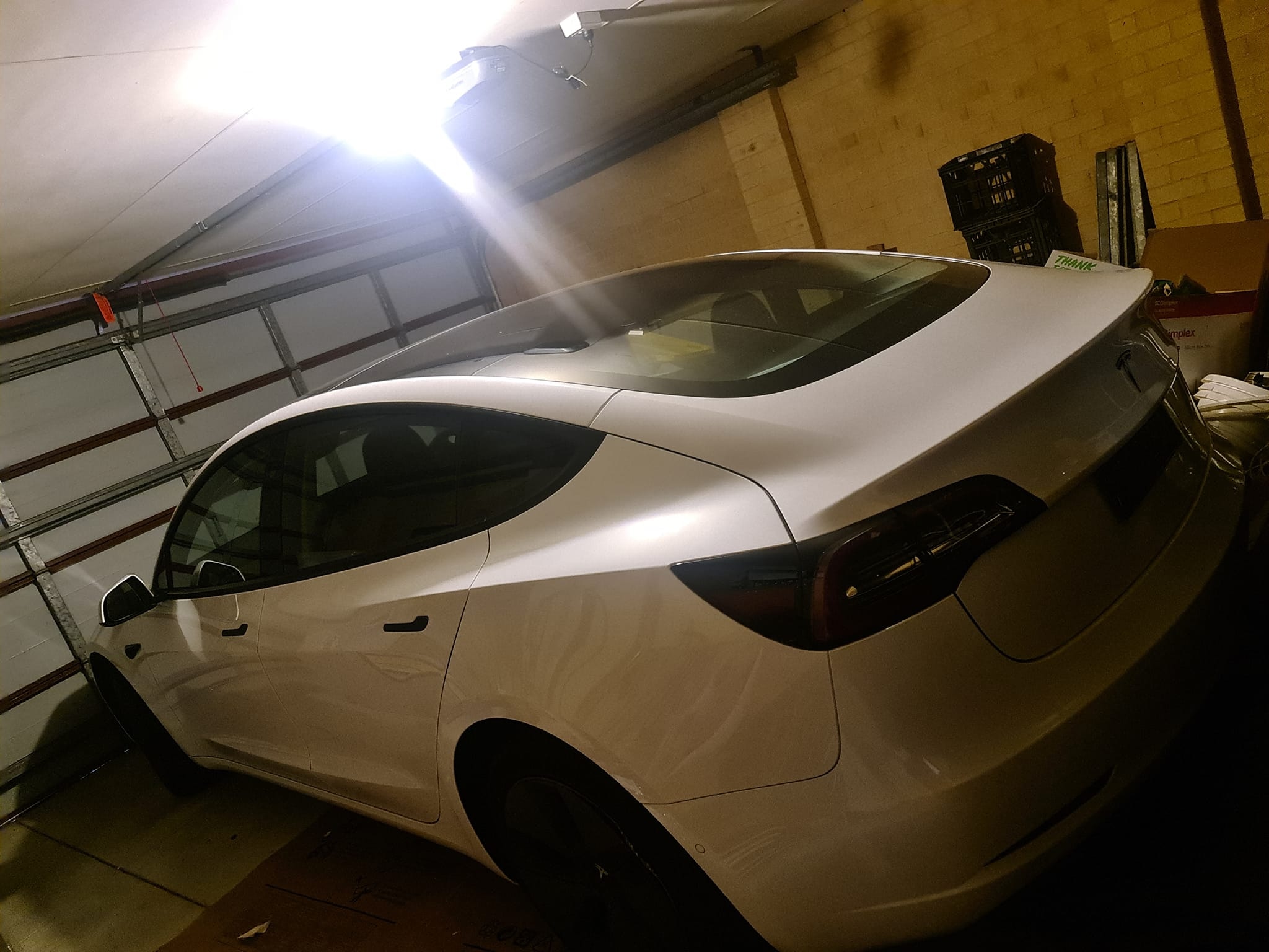 Un coche eléctrico Tesla blanco está aparcado en un aparcamiento subterráneo