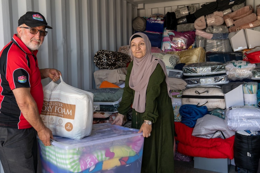 A man and a woman wearing a headscarf inside a large container