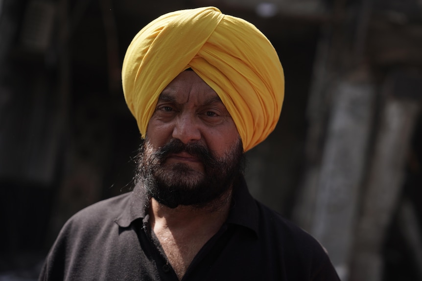 A man with a black beard wearing a yellow turban on his head