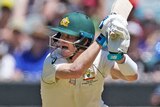 Steve Smith hits a cover drive as the wicket-keeper watches on at the MCG