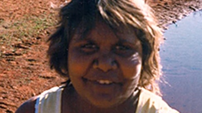 Close image of woman with red sand and water in the background