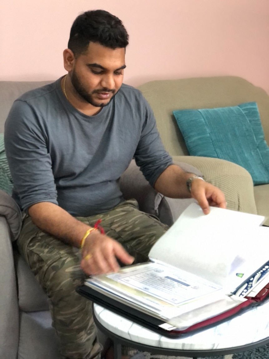 A man sits on a couch reading.