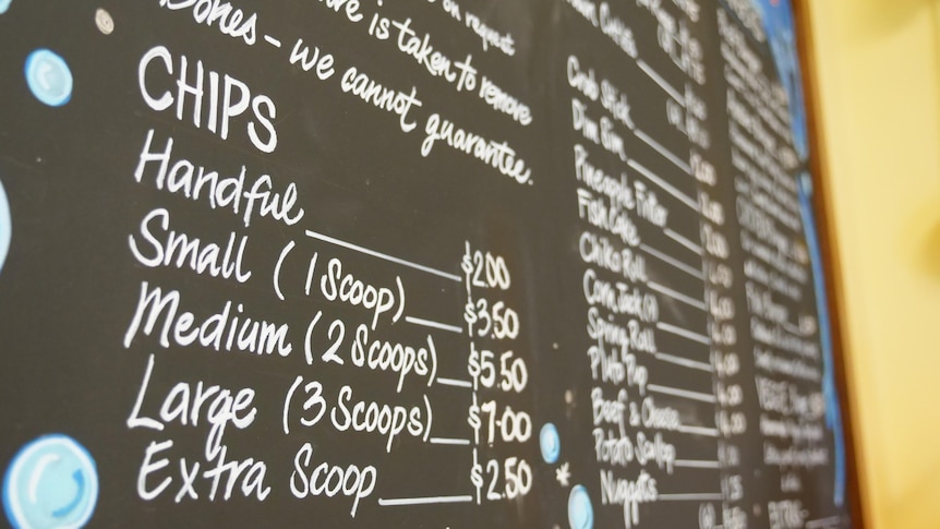 A close up of a blackboard with a menu including chips, sides.