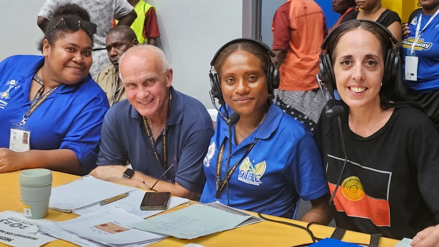 Three women and man at a commentators desk