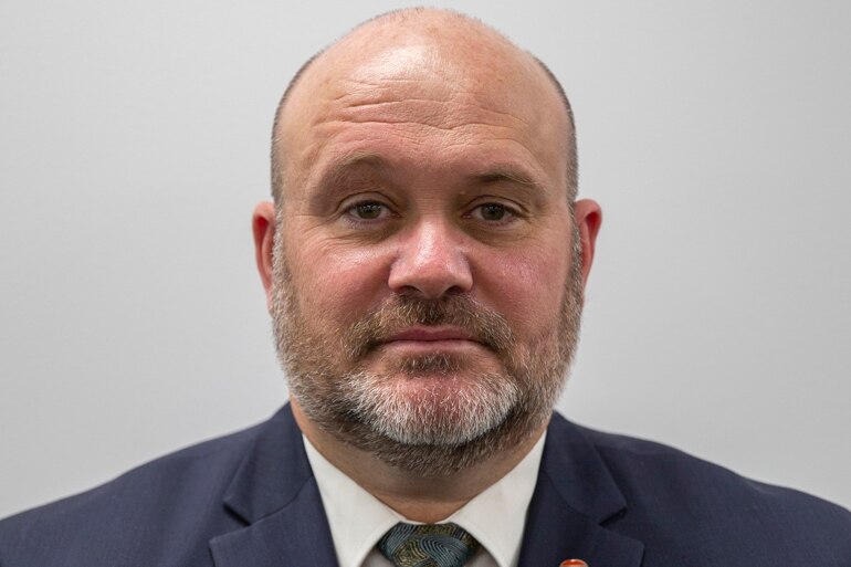 Portrait corporate headshot of man wearing suit looking at camera