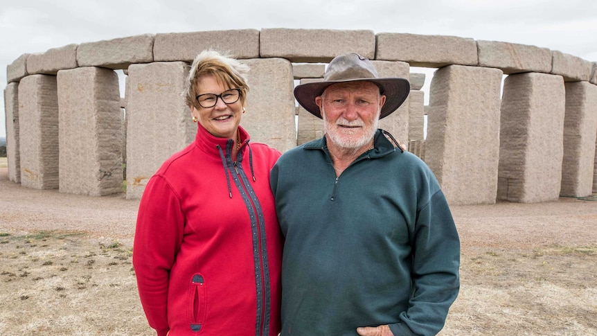A man and woman standing in front of a Stonehenge replica.