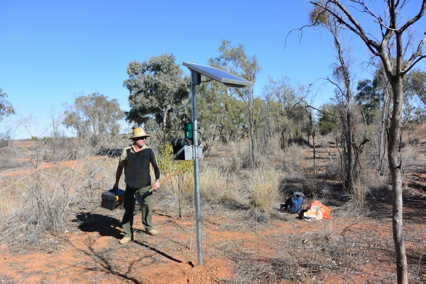 A man using a sound recorder to monitor outback ecosystems.