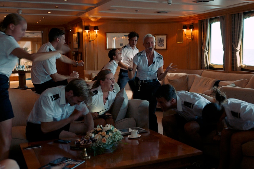 A group of people in sailors uniform surrounding a woman screaming on a boat