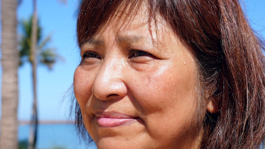 Closeup photo of a woman's face outdoors looking past camera.
