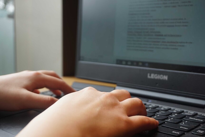 A close up shot of a student typing on a laptop.