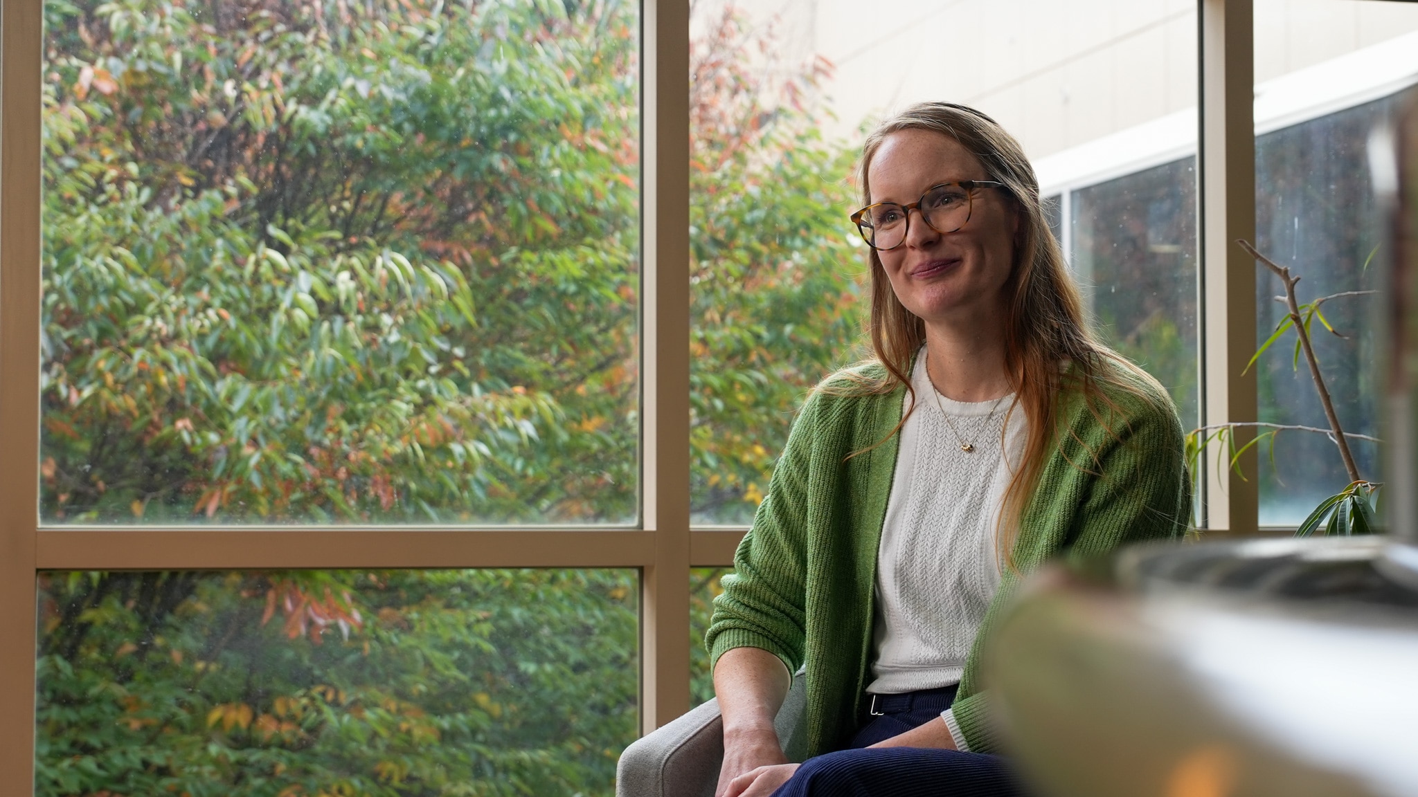 Woman sitting on a chair in front of a window.