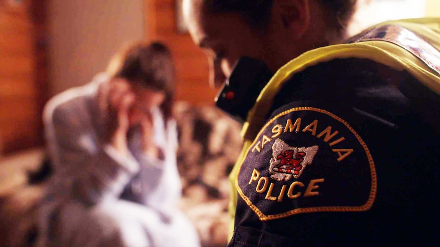 Tasmanian police officer comforts a woman in her home