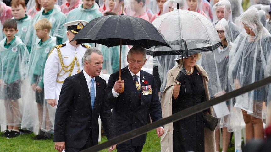 Dr Brendan Nelson walks with Prince Charles and the Duchess of Cornwall in the rain at the Australian War Memorial.