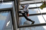 A man climbs up the side of a building