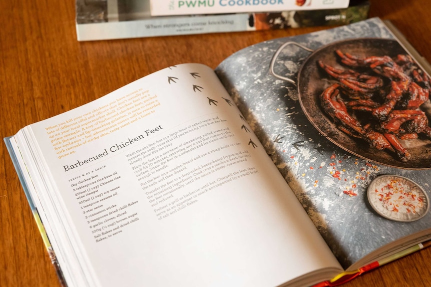 A recipe book lies open on a table showing a recipe for barbequed chicken feet.