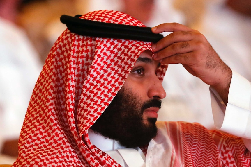 Saudi Arabia's crown prince Mohammed bin Salman lifts his hand to his forehead