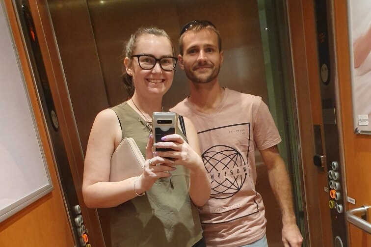 Cassandra Bakes and Andrew Ellis are in a lift and are taking a selfie in the mirror.