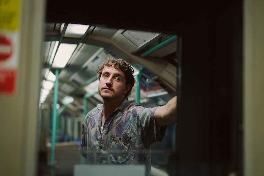 A film still of Paul Mescal standing on the tube. He has a forlorn expression.
