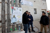 Men mill around a poster of the Palestinian-American killed, January 12, 2022.