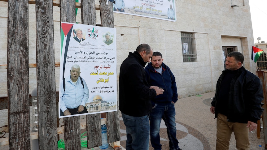 Men mill around a poster of the Palestinian-American killed, January 12, 2022.