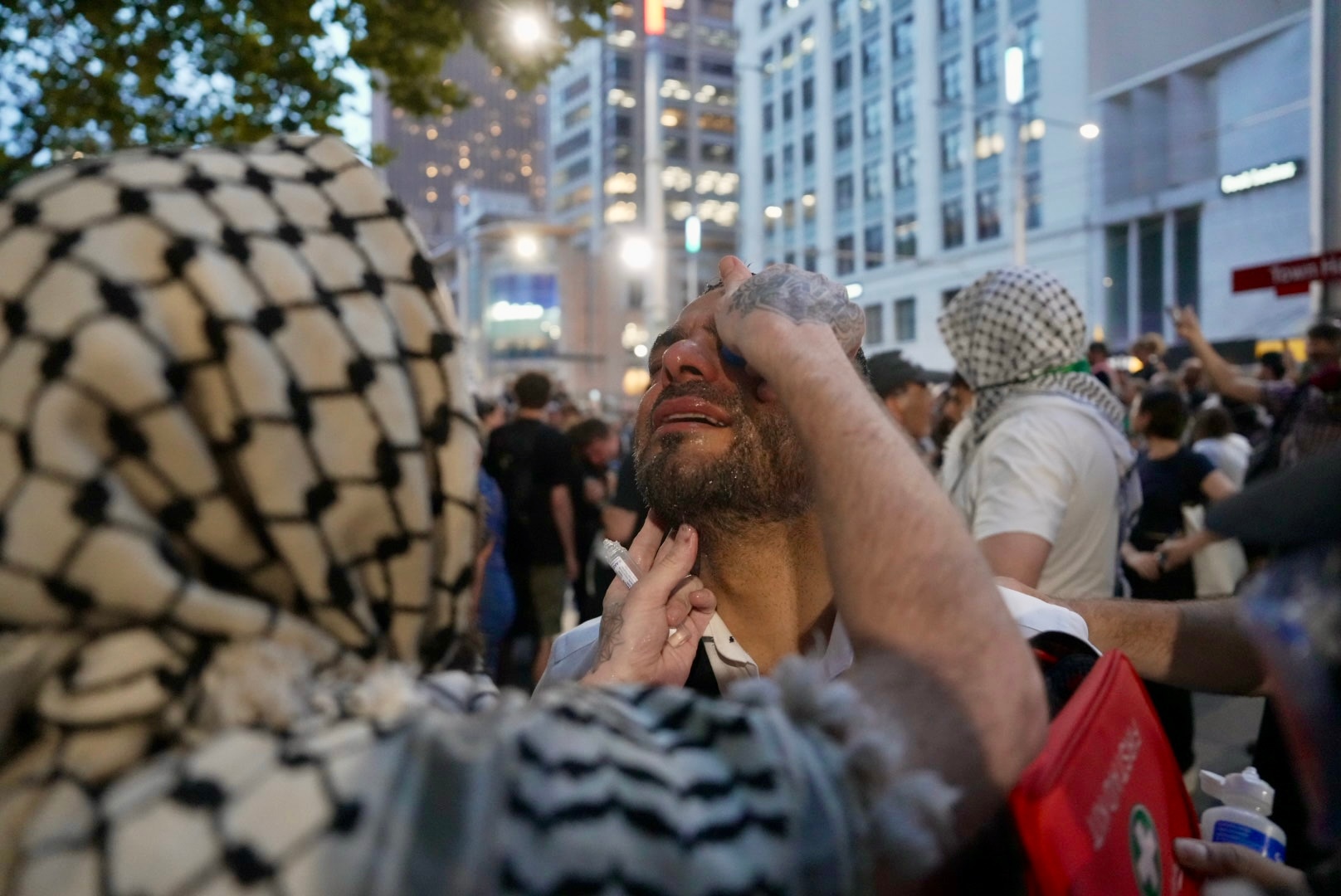 Una persona ayuda a salpicar agua en la cara de un hombre que tiene la cabeza inclinada hacia atrás
