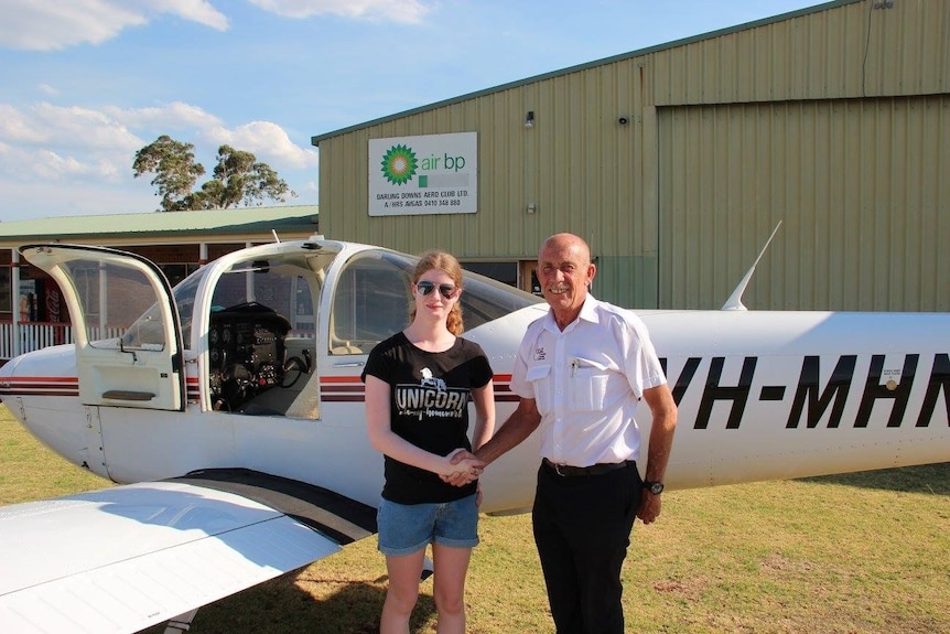 Young woman stands in front of small plane shaking hands with a man, Toowoomba Queensland