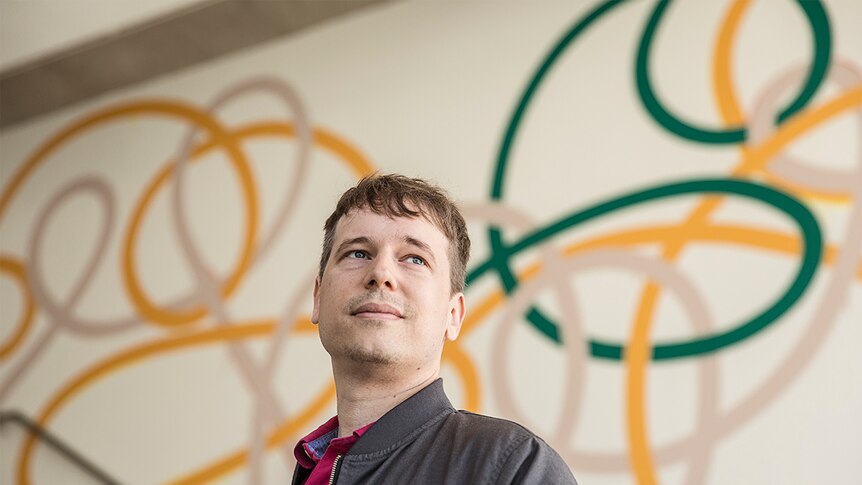 Colour photo of artist Ryan Presley looking off camera and standing at the entrance of the Museum of Contemporary Art in Sydney.