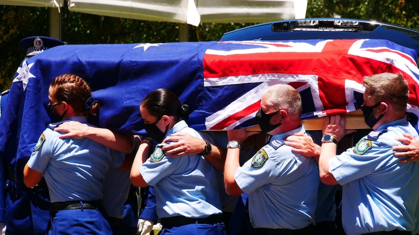Police officers carry a casket draped with an Australian flag.